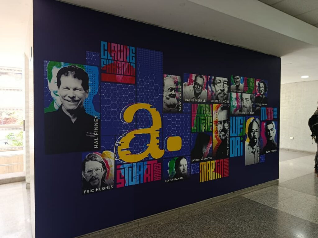 Fotografía del mural que honra la descentralización en la UCAB. Muestra fotos de estas figuras sobre un fondo azul.