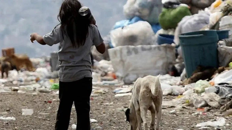 Niña pobre jugando con un perro en un basurero. Imagen de archivo