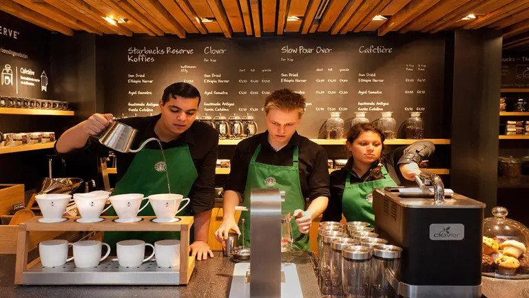 Tres empleados de Starbucks trabajando tras un mostrador. Foto gentileza de Starbucks.