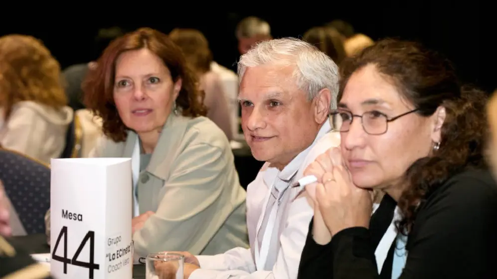 Un hombre junto a 2 mujeres escuchando una capacitación con un cartelque indica que la mesa es la 44