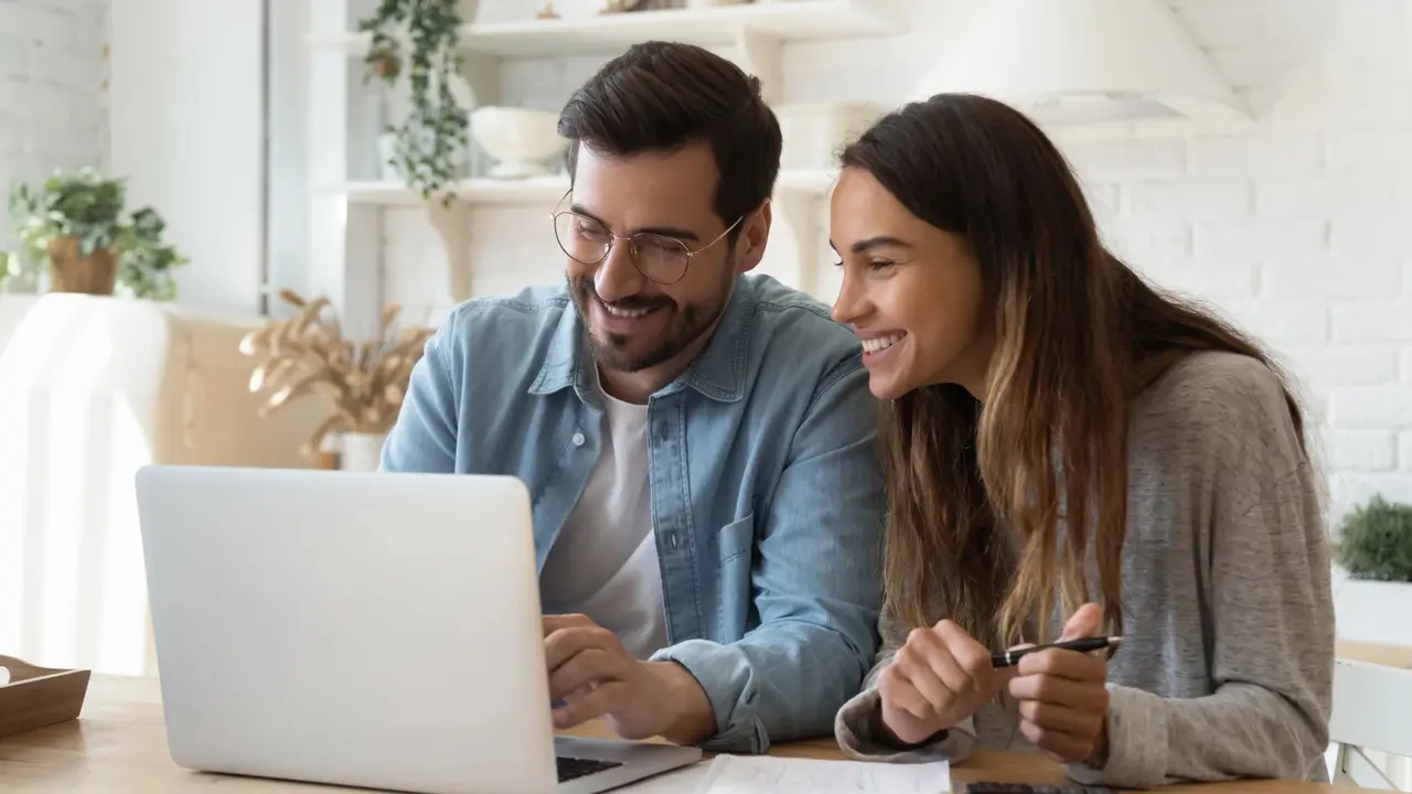 Pareja de emprendedores pyme contentos frente a una computadora. Imagen de archivo.