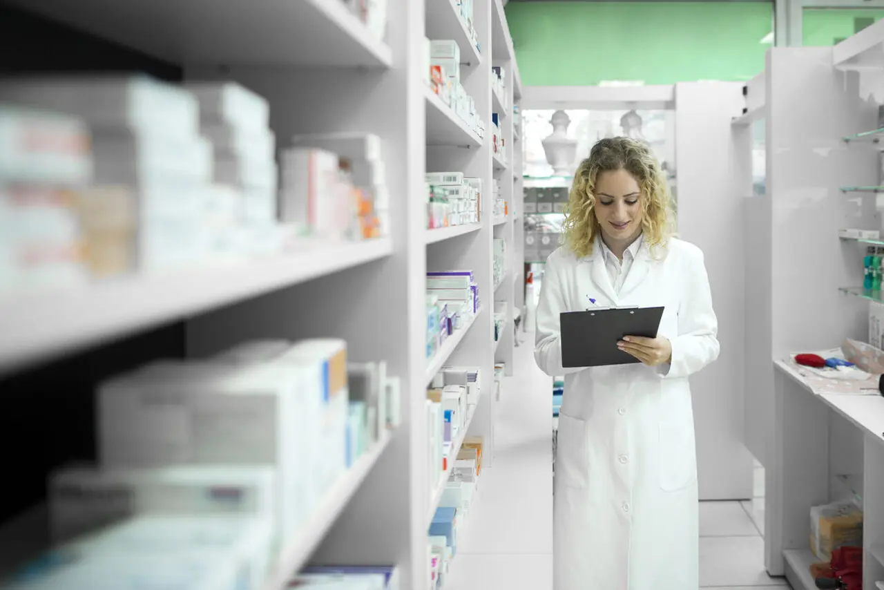 Farmacéutica con planilla y estantes con medicamentos