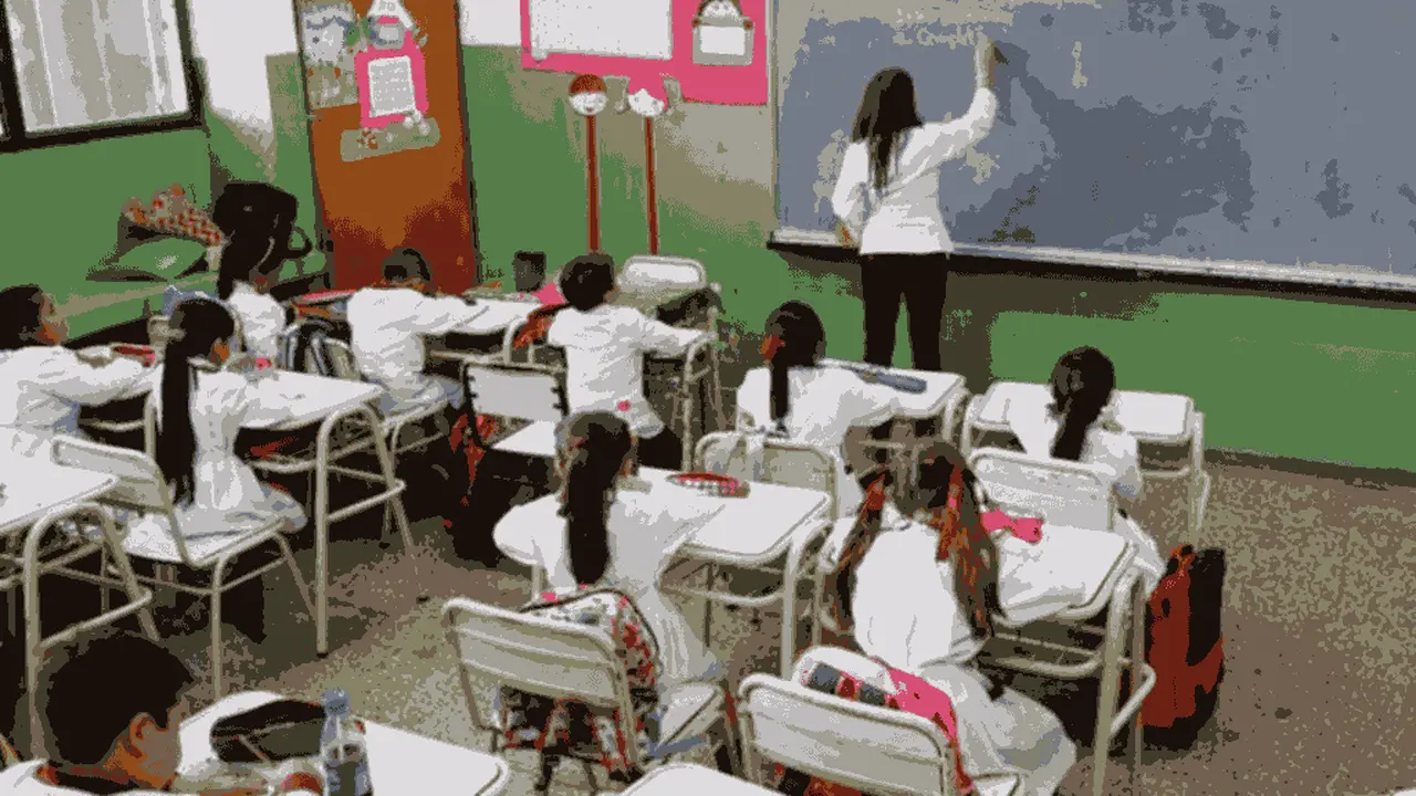 Maestra escribiendo en un pizarrón en un colegio público. Imagen de archivo.